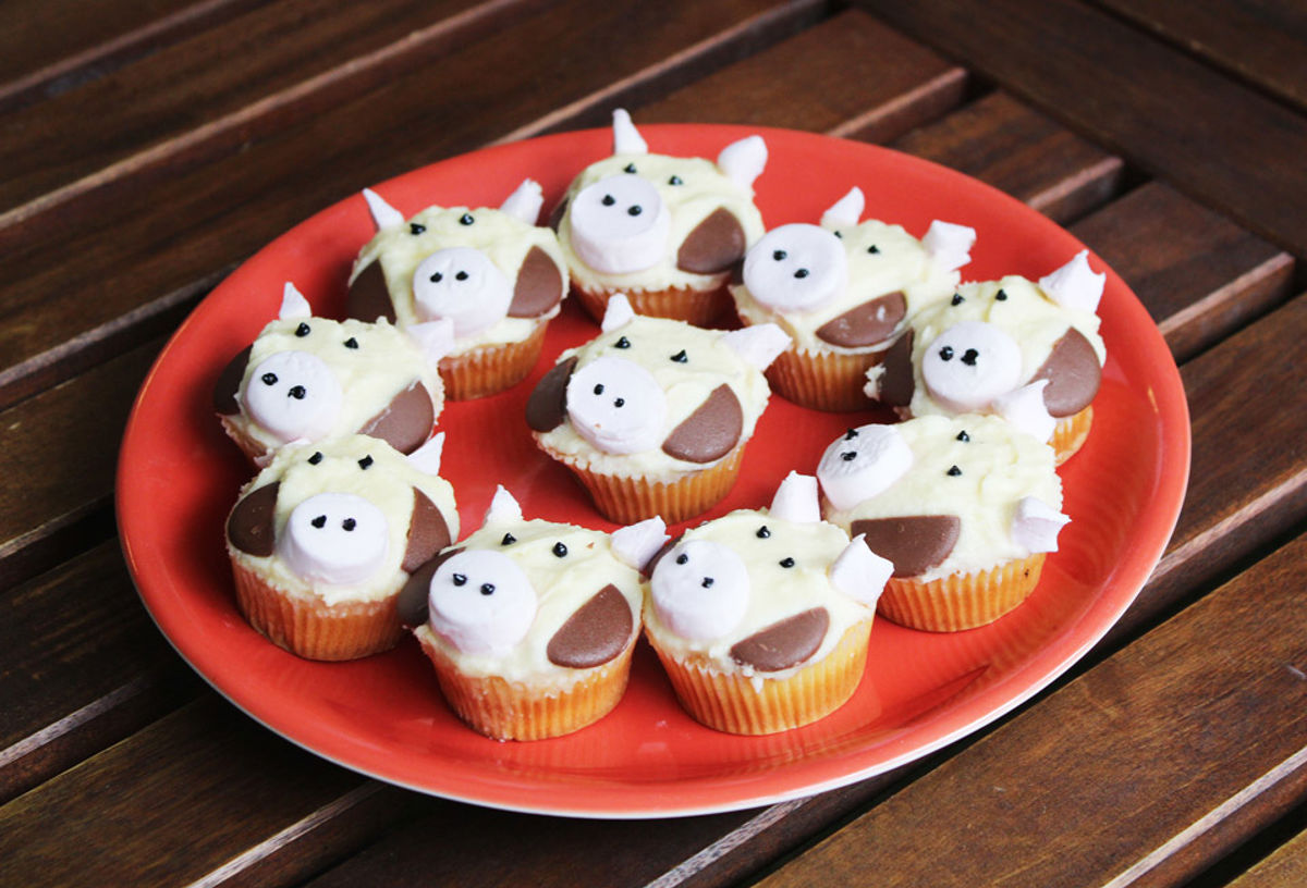 A plate of cupcakes with cow face icing