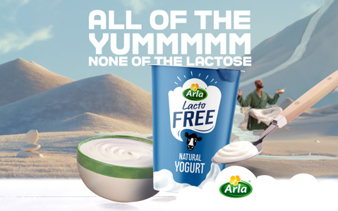 Arla Lacto FREE yogurt container in surreal desert, with yogurt bowl and spoon. Text: 'ALL OF THE YUM NONE OF THE LACTOSE'.