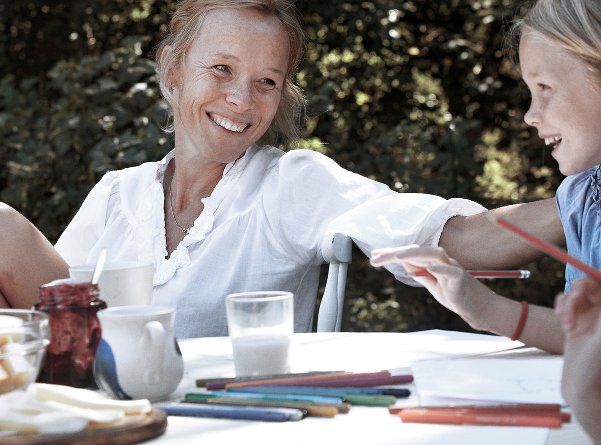 A mother smiling at her child at a garden table