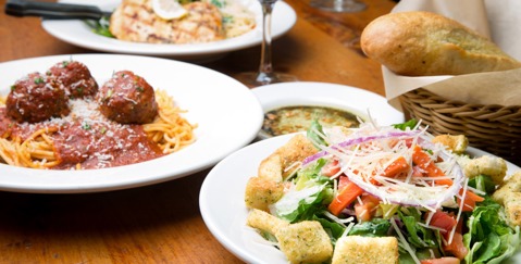 Plated meal featuring meatballs, fish, and salad on a wooden table